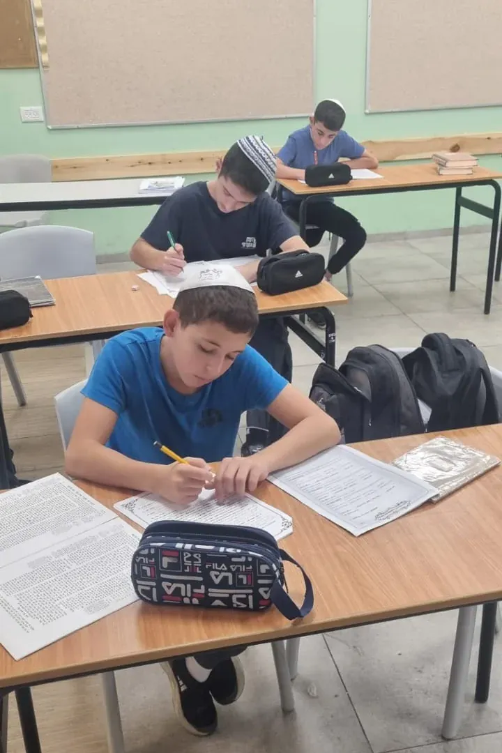 שני תלמידים כותבים ליד שולחנות הכיתה