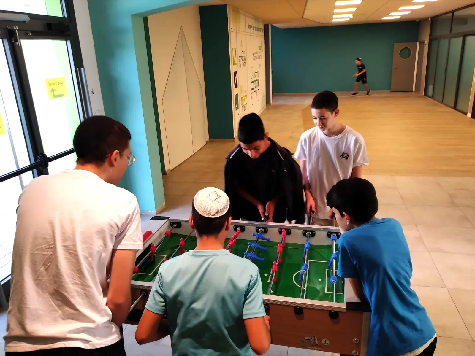 תלמידים משחקים כדורגל שולחן במסדרון