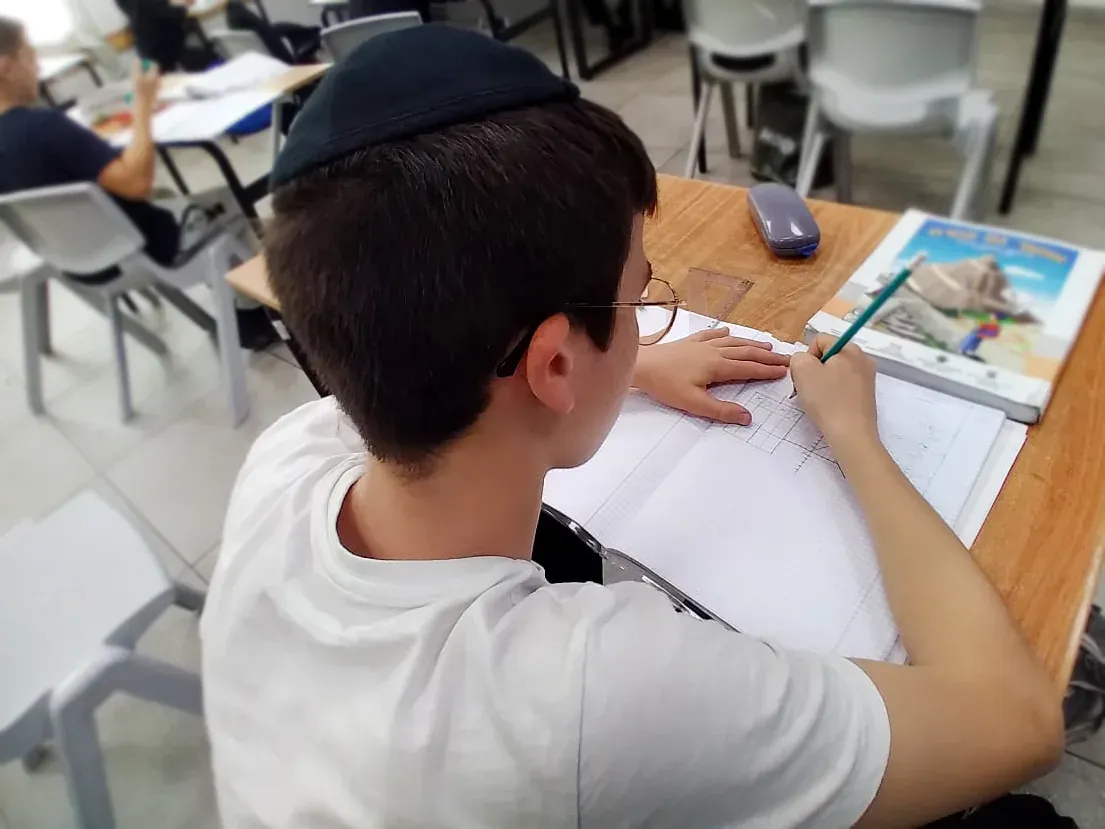תלמיד כותב במחברת בשיעור